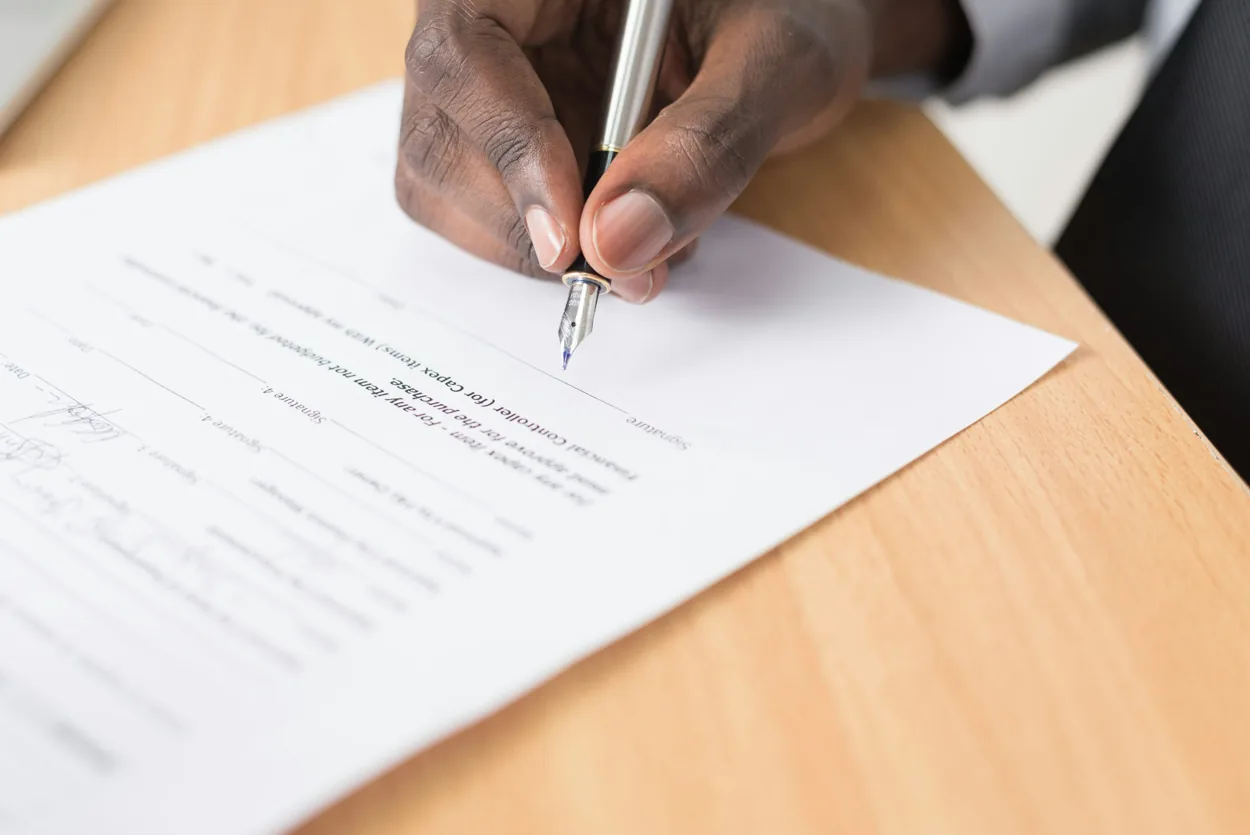 Illustrative photograph of a person writing on paper at a desk